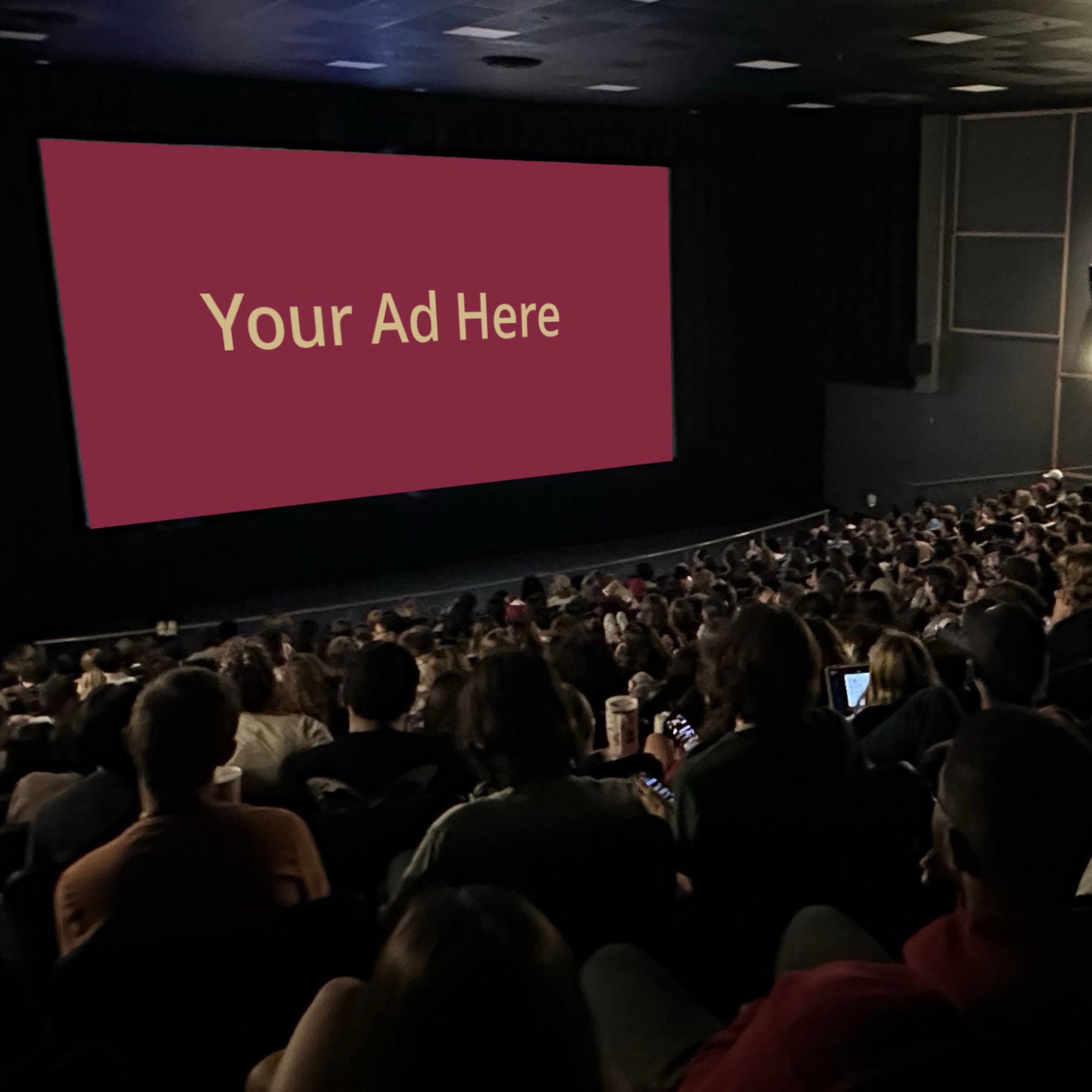 Photo of the ASLC theater with an audience and a graphic on the theater screen that says your ad here.